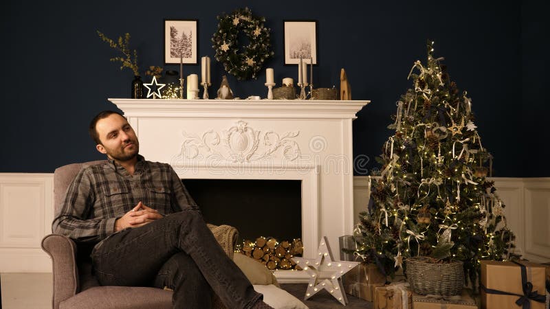 Jeune homme beau barbu de hippie dans roomthinking de Noël des idées de cadeau rêverie photographie stock Jeune homme beau barbu de hippie dans roomthinking de Noël des idées de cadeau rêverie photographie stock
