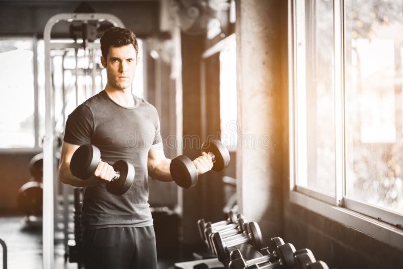 Jeune homme beau caucasien convenable et grand muscle dans les vêtements de sport Jeune homme tenant l'haltère pendant une classe images stock Jeune homme beau caucasien convenable et grand muscle dans les vêtements de sport Jeune homme tenant l'haltère pendant une classe images stock