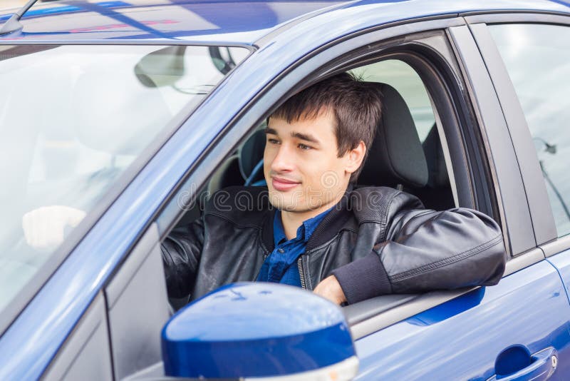 Jeune homme beau s'asseyant dans sa voiture image stock Jeune homme beau s'asseyant dans sa voiture image stock