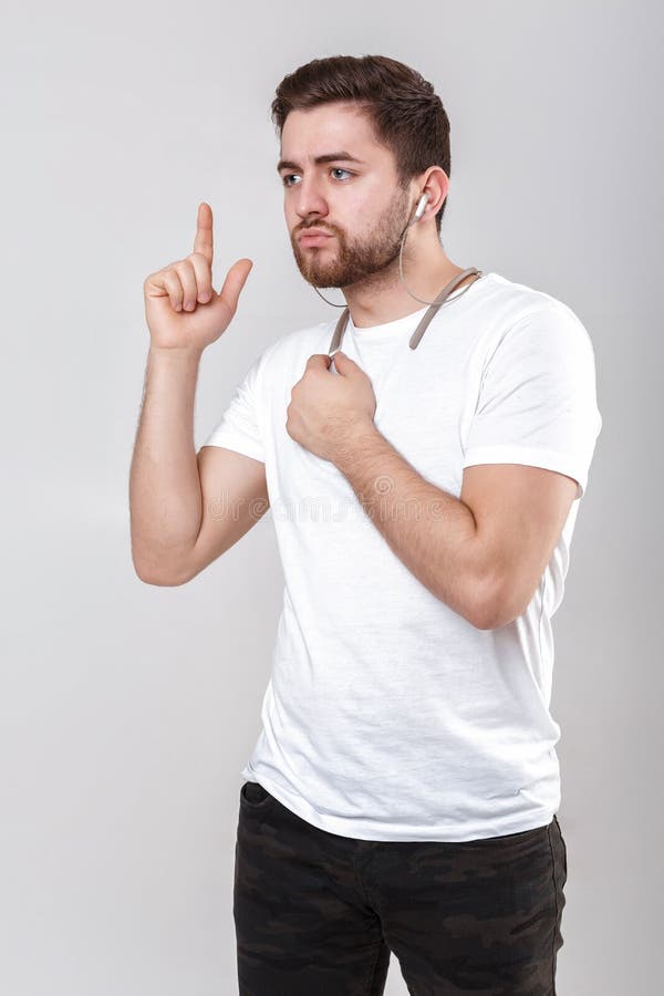 Jeune homme bel avec la barbe dans le T-shirt écoutant la musique sur des écouteurs image libre de droits Jeune homme bel avec la barbe dans le T-shirt écoutant la musique sur des écouteurs image libre de droits