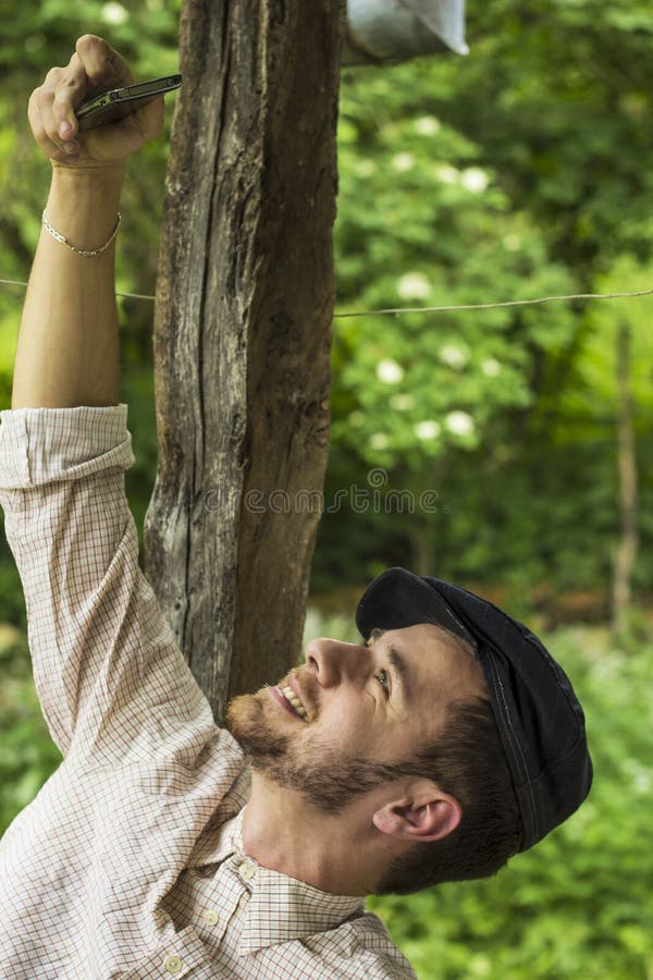Jeune homme bel avec le chapeau prenant l'individu avec le téléphone photo stock Jeune homme bel avec le chapeau prenant l'individu avec le téléphone photo stock