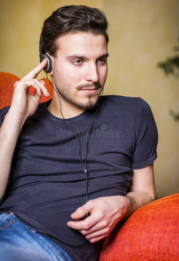 Jeune homme bel ?coutant la musique sur des ?couteurs images stock Jeune homme bel ?coutant la musique sur des ?couteurs images stock