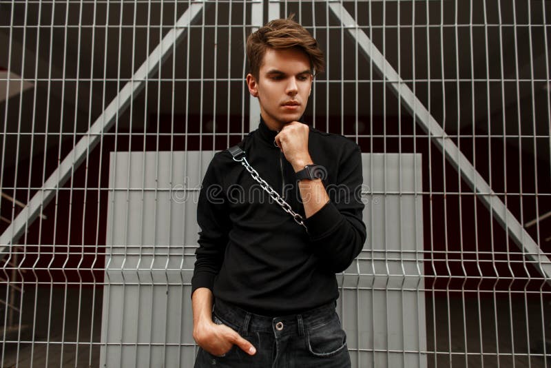 Jeune homme bel dans la pose occasionnelle noire de vêtements de sport photos stock Jeune homme bel dans la pose occasionnelle noire de vêtements de sport photos stock