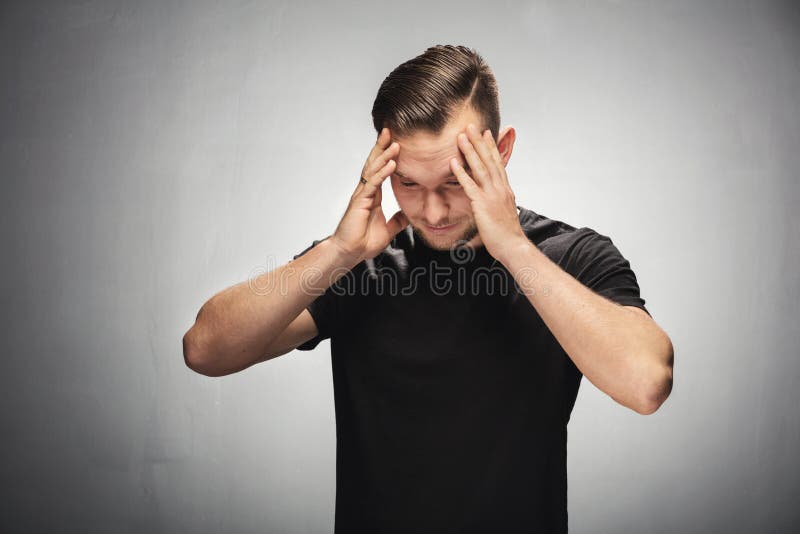 Young man grabbing his head, looking both troubled and confused. Studio portrait. Young man grabbing his head, looking both troubled and confused. Studio portrait.