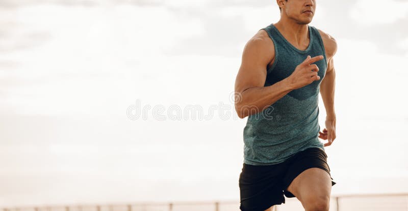 Jeune homme courant le long d'une promenade de bord de la mer image libre de droits Jeune homme courant le long d'une promenade de bord de la mer image libre de droits