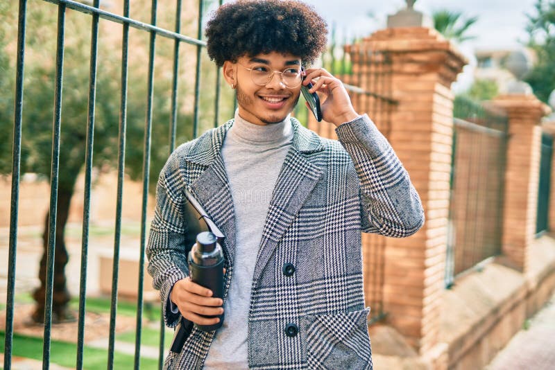 Jeune homme d'affaires africain américain parlant sur le smartphone tenant une bouteille d'eau à la ville photographie stock