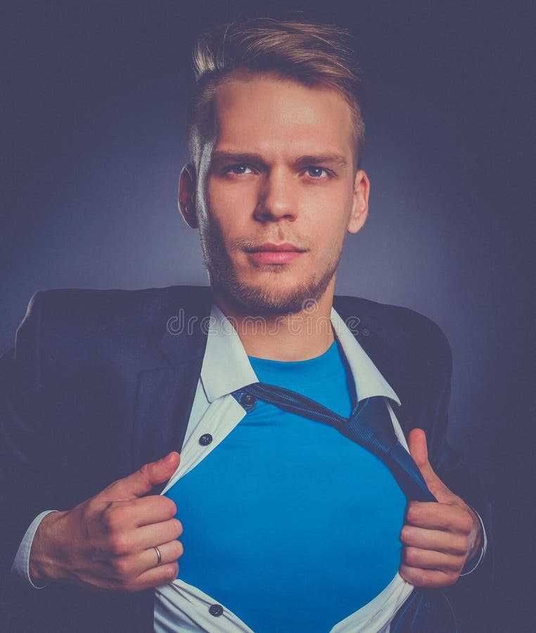 Jeune homme d'affaires agissant comme un superhéros et déchirant sa chemise, d'isolement sur le fond gris image stock Jeune homme d'affaires agissant comme un superhéros et déchirant sa chemise, d'isolement sur le fond gris image stock