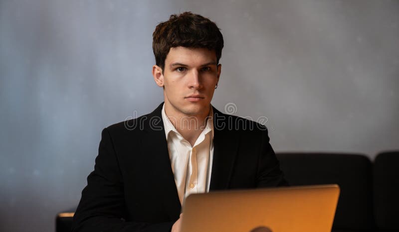 Jeune homme d'affaires au bureau qui travaille tard le soir, homme assis au bureau, avec un ordinateur portable qui regarde loin d photo libre de droits