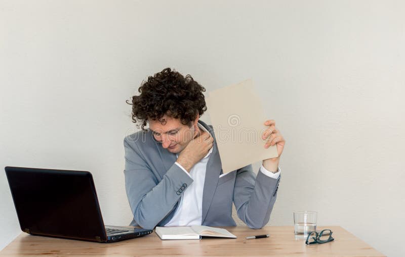 Jeune homme d'affaires caucasien tenant une page blanche devant le mur clair vide image stock Jeune homme d'affaires caucasien tenant une page blanche devant le mur clair vide image stock