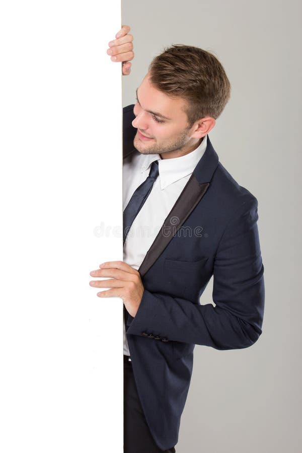 Jeune homme d'affaires dans le costume noir regardant le tableau blanc vide photographie stock libre de droits Jeune homme d'affaires dans le costume noir regardant le tableau blanc vide photographie stock libre de droits