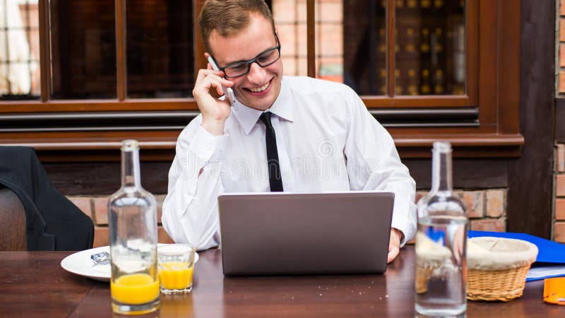 Smiling young businessman making a call with his smartphone in a restaurant. Smiling young businessman making a call with his smartphone in a restaurant