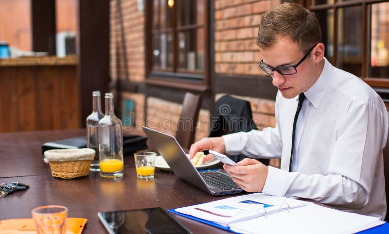 Smiling young businessman making a call with his smartphone in a restaurant. Smiling young businessman making a call with his smartphone in a restaurant