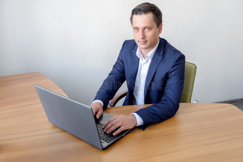 Jeune homme d'affaires heureux utilisant l'ordinateur portable à son bureau images libres de droits Jeune homme d'affaires heureux utilisant l'ordinateur portable à son bureau images libres de droits