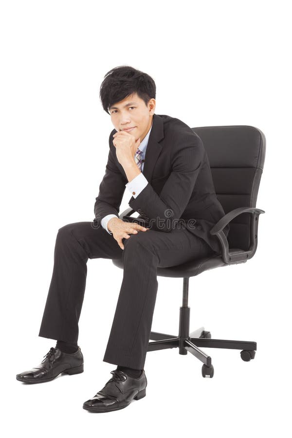 Jeune homme d'affaires pensant et s'asseyant dans une chaise photo stock Jeune homme d'affaires pensant et s'asseyant dans une chaise photo stock