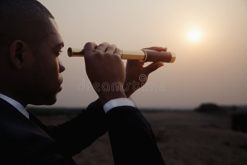 Jeune homme d'affaires regardant par le télescope au milieu du désert