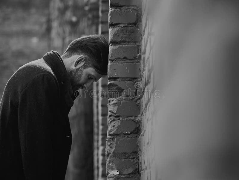 Jeune homme d?prim? frustrant pr?s du mur de briques semblant f?ch? Portrait dramatique modifié la tonalité triste de plan rappro photo libre de droits Jeune homme d?prim? frustrant pr?s du mur de briques semblant f?ch? Portrait dramatique modifié la tonalité triste de plan rappro photo libre de droits