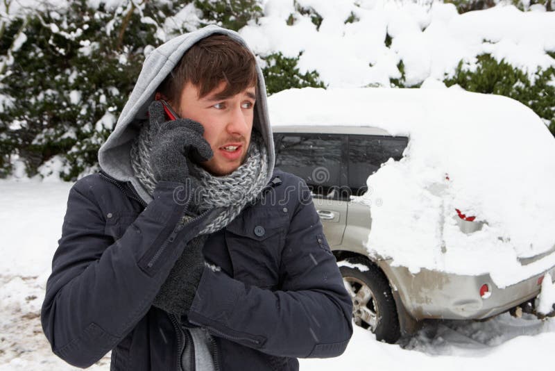 Jeune homme dans la neige avec le véhicule décomposé