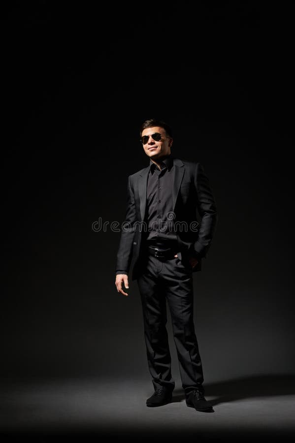 Jeune homme dans le procès et des lunettes de soleil noirs image libre de droits Jeune homme dans le procès et des lunettes de soleil noirs image libre de droits