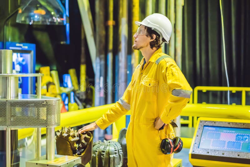 Jeune homme dans un uniforme jaune, les verres et le casque de travail dans le milieu industriel, la plateforme p?troli?re ou l'u photographie stock Jeune homme dans un uniforme jaune, les verres et le casque de travail dans le milieu industriel, la plateforme p?troli?re ou l'u photographie stock