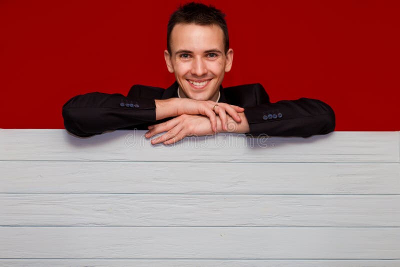 Jeune homme de sourire avec le panneau rouge vide de signe Bannière belle de participation d'homme d'affaires avec le copyspace photo libre de droits Jeune homme de sourire avec le panneau rouge vide de signe Bannière belle de participation d'homme d'affaires avec le copyspace photo libre de droits