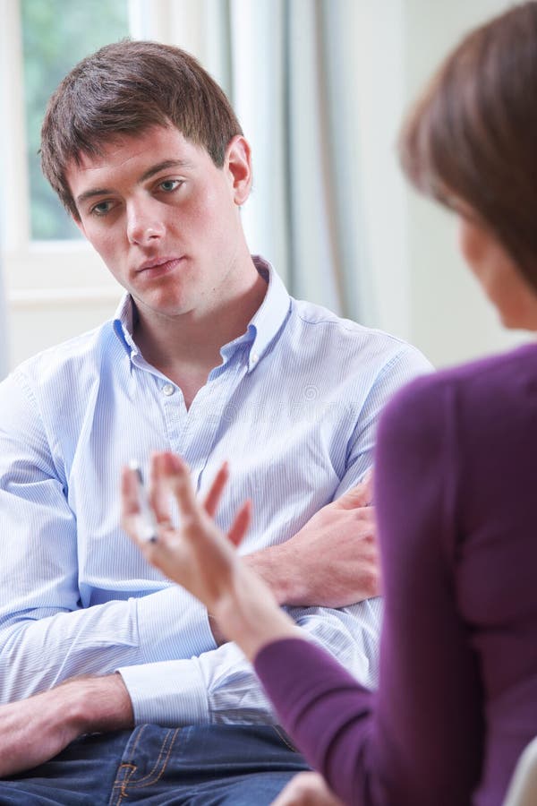 Jeune homme déprimé parlant au conseiller photo stock