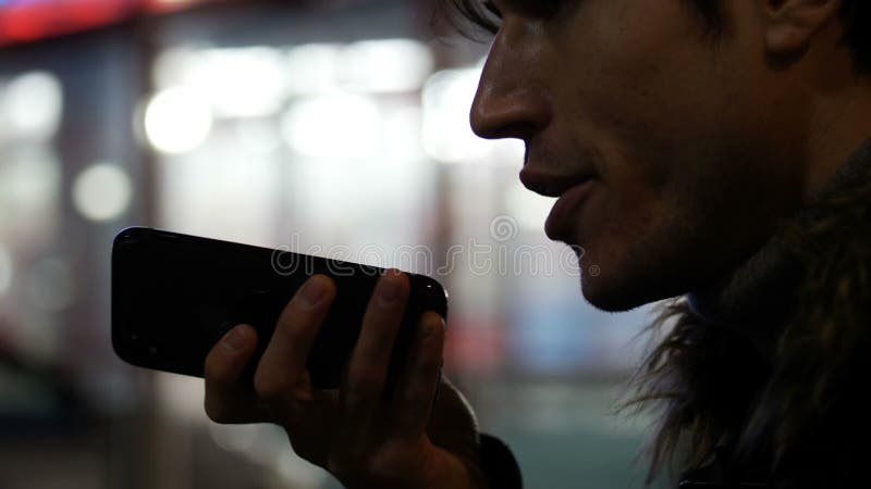 Jeune homme envoyant le message de voix avec le téléphone portable