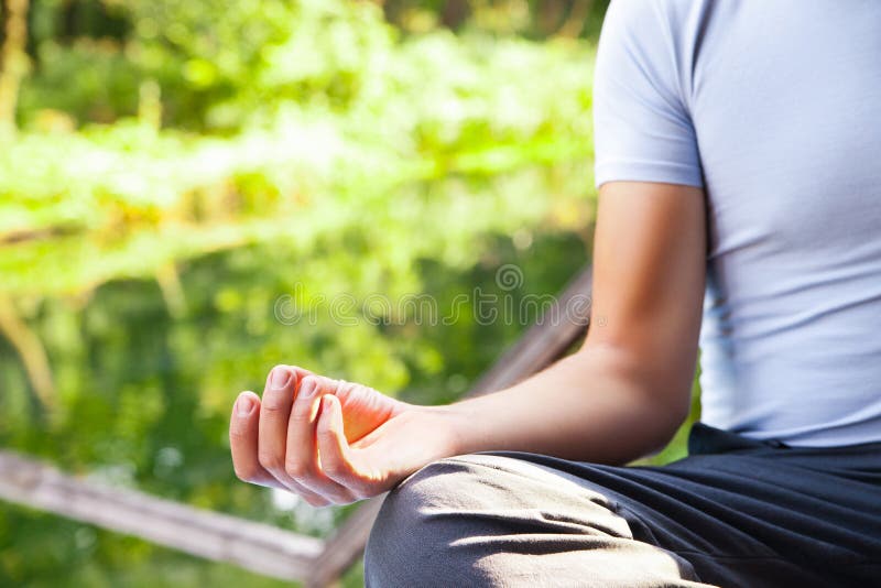 Jeune homme faisant la pose de lotus de yoga en parc photo stock Jeune homme faisant la pose de lotus de yoga en parc photo stock