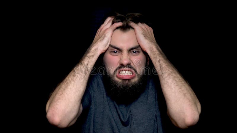Jeune homme fâché criant, exprimant des émotions négatives, arrachant ses cheveux, d'isolement sur le fond noir Fermez-vous vers photos stock Jeune homme fâché criant, exprimant des émotions négatives, arrachant ses cheveux, d'isolement sur le fond noir Fermez-vous vers photos stock