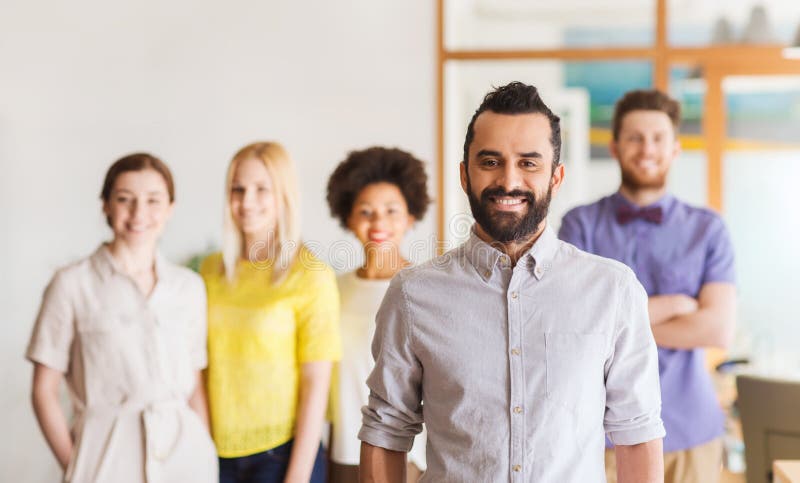 Jeune homme heureux au-dessus d'équipe créative dans le bureau image stock Jeune homme heureux au-dessus d'équipe créative dans le bureau image stock