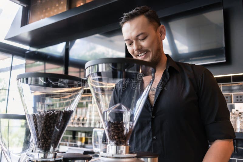 Jeune homme heureux préparant l'expresso tout en travaillant comme barman dans a photographie stock libre de droits Jeune homme heureux préparant l'expresso tout en travaillant comme barman dans a photographie stock libre de droits