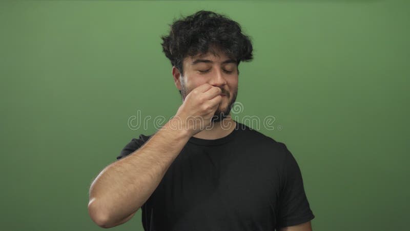 Jeune homme hispanique à la barbe envoyant un geste de baiser avec ses doigts sur un fond vert vif banque de vidéos