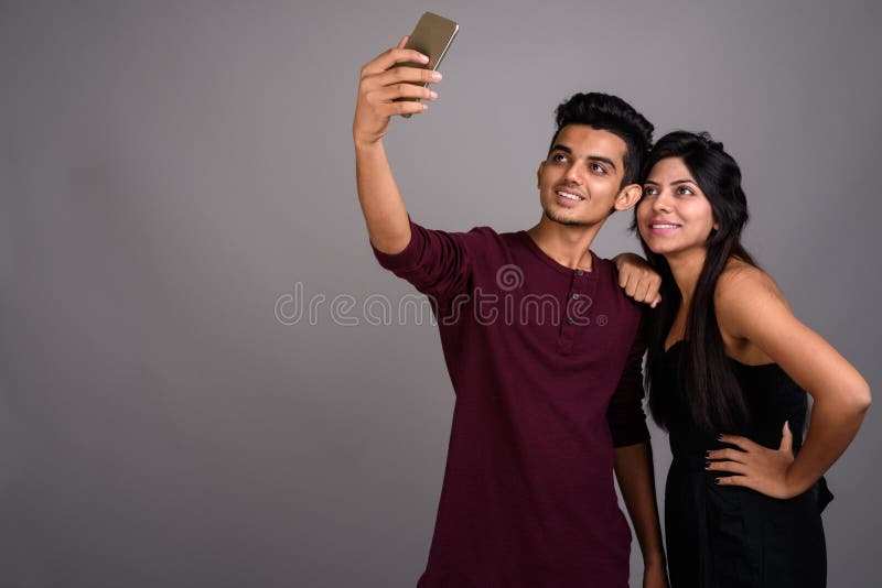 Jeune homme indien et jeune femme indienne ensemble contre le Ba gris photographie stock Jeune homme indien et jeune femme indienne ensemble contre le Ba gris photographie stock