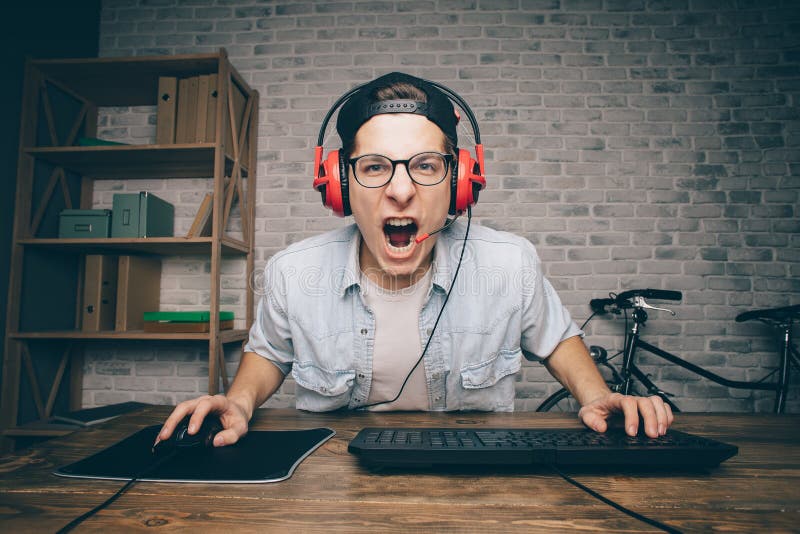 Jeune homme jouant le jeu à la maison et coulant la vidéo de playthrough ou de revue du projet photo libre de droits Jeune homme jouant le jeu à la maison et coulant la vidéo de playthrough ou de revue du projet photo libre de droits