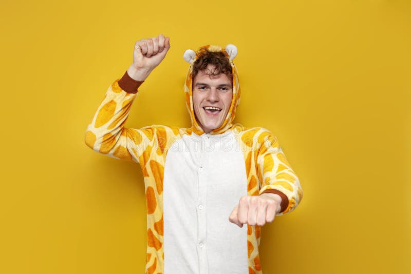 Jeune homme joyeux dans drôles enfants girafe pyjamas danse sur fond jaune homme en costume animal photo libre de droits