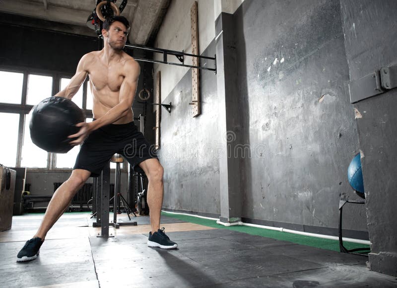 Jeune homme musculaire décent fort faisant le medicine-ball de lancement sur le mur du crossfit formant la séance d'exercice purs photos libres de droits