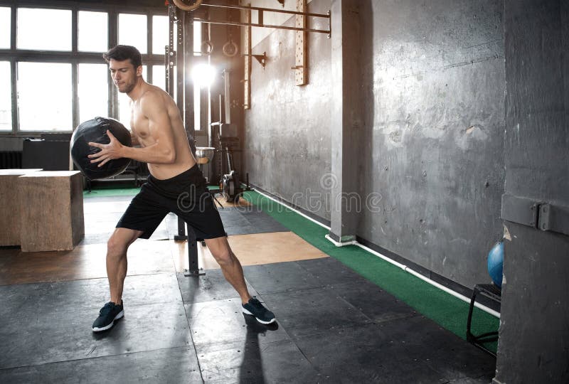Jeune homme musculaire décent fort faisant le medicine-ball de lancement sur le mur du crossfit formant la séance d'exercice purs image stock