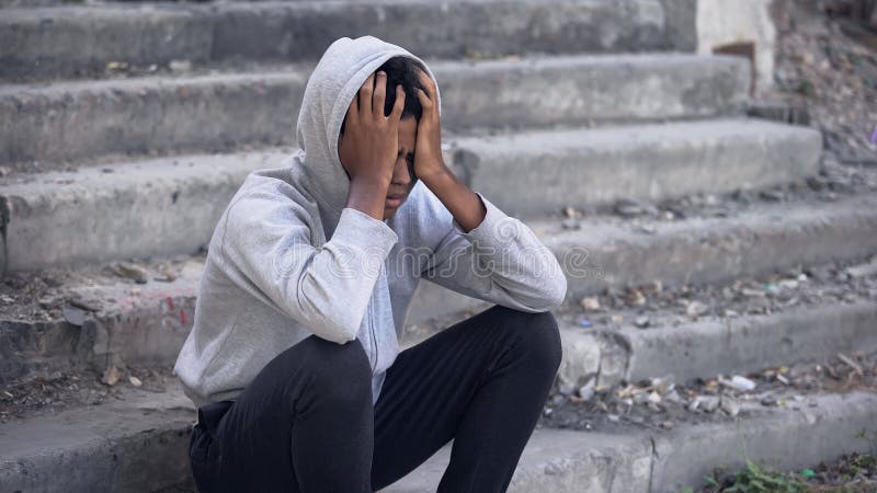 Jeune homme noir déprimé assis à l'extérieur, maltraitance émotionnelle, problème familial images stock