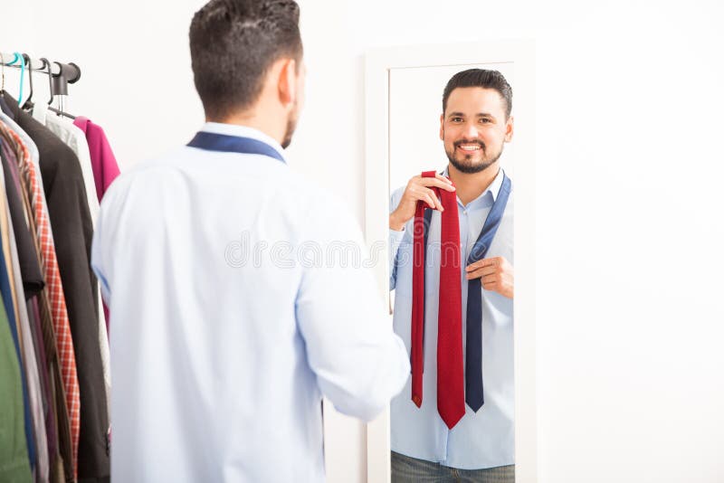 Jeune homme obtenant habillé devant un miroir photos stock Jeune homme obtenant habillé devant un miroir photos stock