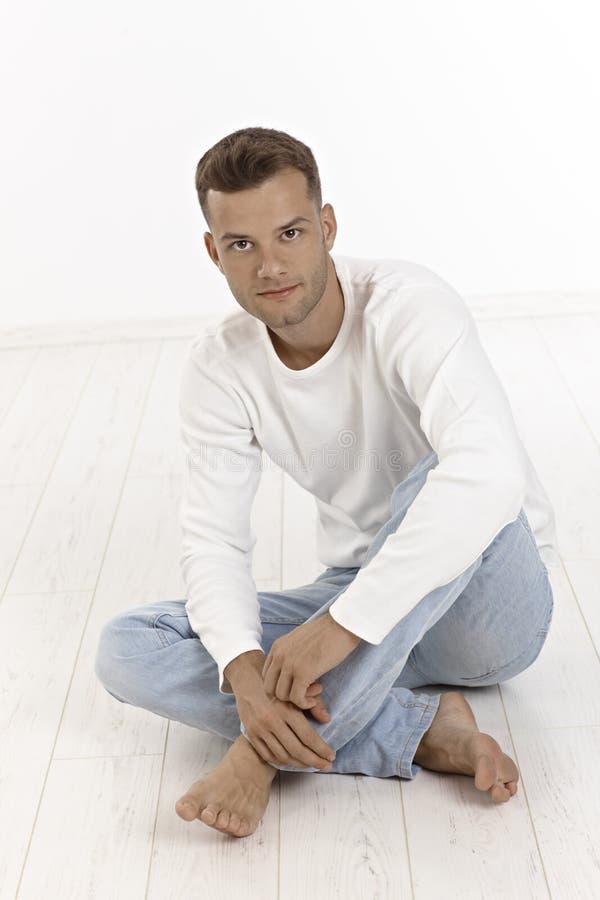 Jeune homme occasionnel s'asseyant sur le plancher photos stock Jeune homme occasionnel s'asseyant sur le plancher photos stock