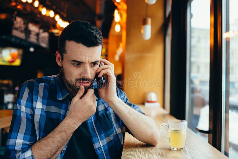 Jeune homme parlant au téléphone en café photo stock Jeune homme parlant au téléphone en café photo stock