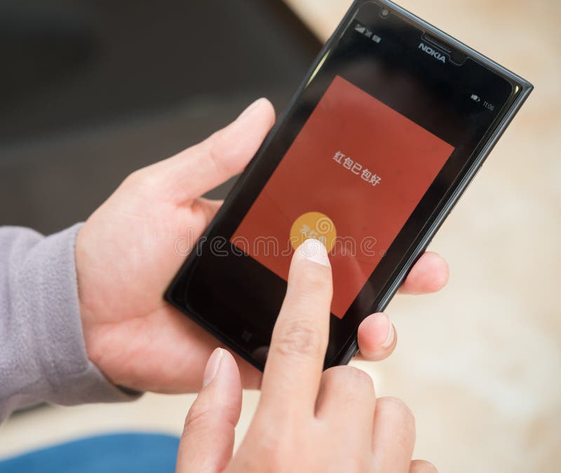 Jeune homme préparant la poche rouge sur le mobile sur WeChat pour la nouvelle année chinoise images stock Jeune homme préparant la poche rouge sur le mobile sur WeChat pour la nouvelle année chinoise images stock