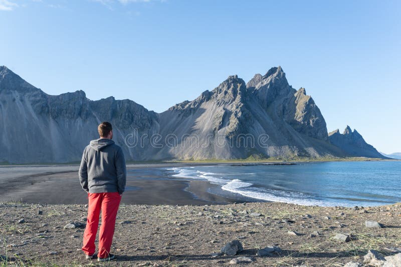 Jeune homme regardant une plage scénique en Islande images stock Jeune homme regardant une plage scénique en Islande images stock
