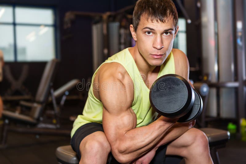 Jeune homme s'exerçant avec le poids dans le gymnase images stock Jeune homme s'exerçant avec le poids dans le gymnase images stock