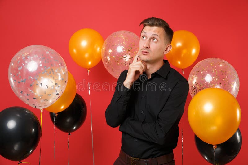 Jeune homme songeur dans la pensée classique noire de chemise, recherchant, gardant le doigt sur le menton sur les ballons à air images stock Jeune homme songeur dans la pensée classique noire de chemise, recherchant, gardant le doigt sur le menton sur les ballons à air images stock