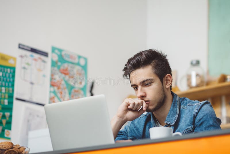 Jeune homme sérieux avec la barbe travaillant sur l'ordinateur portable photos libres de droits Jeune homme sérieux avec la barbe travaillant sur l'ordinateur portable photos libres de droits