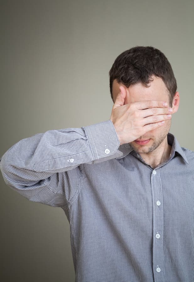 Jeune homme triste cachant son visage avec la main images stock Jeune homme triste cachant son visage avec la main images stock