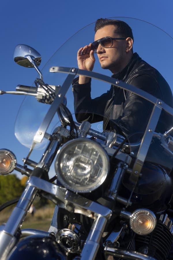 Jeune homme utilisant une veste en cuir noire, les lunettes de soleil et les jeans s images stock Jeune homme utilisant une veste en cuir noire, les lunettes de soleil et les jeans s images stock