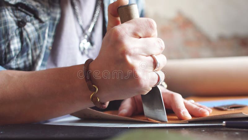 Jeune homme à l'aide d'un couteau spécial pour couper le cuir