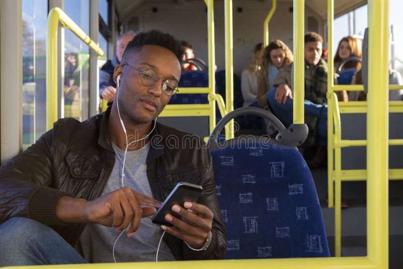 Jeune homme à l'aide d'un smartphone sur l'autobus photo libre de droits Jeune homme à l'aide d'un smartphone sur l'autobus photo libre de droits