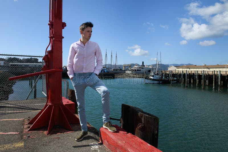 Jeune homme à la mode adulte utilisant le pantalon bleu et le T-shirt classique tenant sur la poire de ville une pensée photographie stock Jeune homme à la mode adulte utilisant le pantalon bleu et le T-shirt classique tenant sur la poire de ville une pensée photographie stock